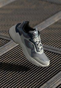 Gray sneaker with a chunky design, featuring a mix of materials including leather and mesh, laces, and a logo on the side.