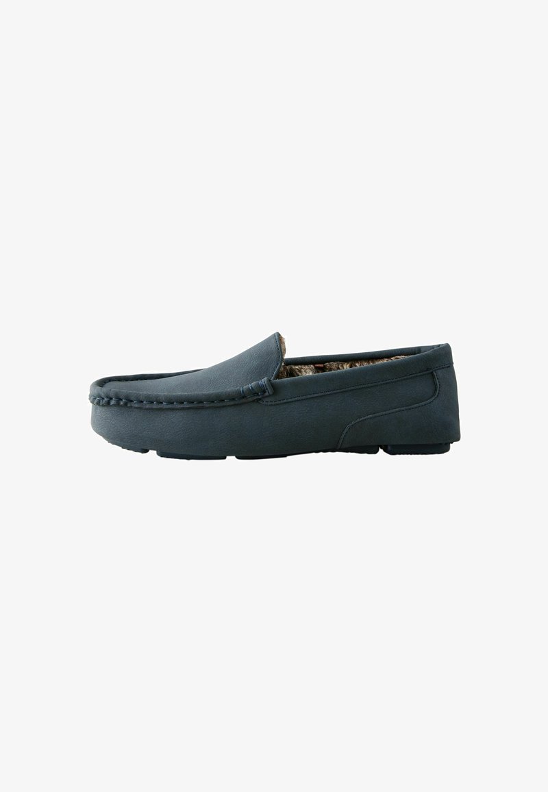 Chaussure slip-on marine en matériau texturé, avec une semelle plate et une couture subtile le long du bord supérieur pour plus de détails.