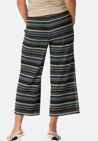 Pantalons larges rayés en mélange de coton, arborant des motifs en zigzag vert, bleu, crème et bourgogne. Longueur cheville avec fentes sur les côtés.