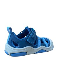 Zapato deportivo azul con parte superior suave, correa de Velcro, cortes para ventilación y una suela blanca con acentos azules.