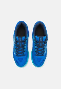 Scarpe sportive blu con tomaia in rete, progettate con una finitura strutturata, lacci scuri a contrasto e suola azzurra chiara. Nessun logo visibile.