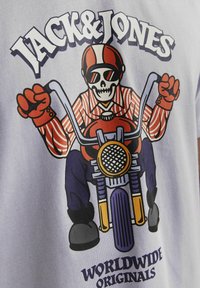 Lys blå t-shirt med grafik af et skelet i en stribet skjorte og solbriller på en motorcykel. Teksten lyder "JACK & JONES."
