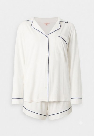 Haut de pyjama blanc à manches longues avec boutons, passepoil bleu marine et short assorti avec bordure bleu marine sur fond uni.