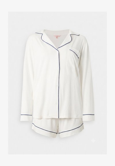 Haut de pyjama blanc à manches longues avec boutons, passepoil bleu marine et short assorti avec bordure bleu marine sur fond uni.