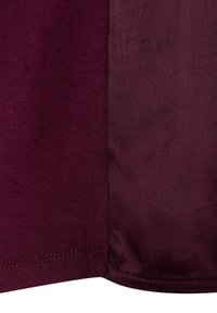 Burgundy fabric with a smooth, matte texture on the left and a satin finish on the right, featuring clean stitching along the edges.