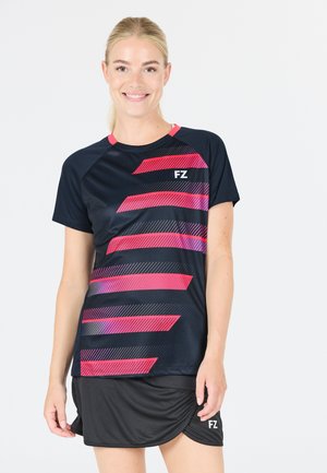 Kortærmet sportstop i marineblå med pink skråstriber og logo. Stoffet fremstår glat og let og er sat sammen med en sort nederdel.