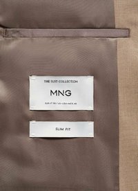 Oznake na gladkem tekstilnem ozadju; zgornja oznaka prikazuje "KOLIČINA OBLAČIL MNG EUR-IT 50 / UK-USA-MEX 40," spodnja oznaka pa pokaže "OZENČENA KROJ."