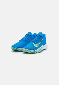 Blue athletic shoes with a textured upper, yellow accents, and a multicolored printed sole featuring a wave pattern.