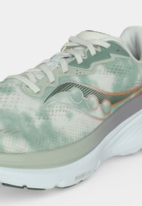 Chaussure de course vert clair et blanc avec texture à motifs, lacets blancs et semelle blanche épaisse étiquetée PWRRUN.