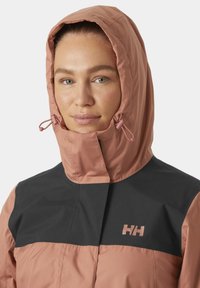 Chaqueta resistente a la intemperie en rosa y negro con cuello alto y capucha ajustable. Presenta una textura suave y un logo en el pecho.
