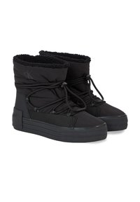 Zapatillas altas negras de textil con un cuello forrado de peluche, cordones elásticos y una suela gruesa de goma con textura rayada.