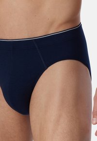 Caleçon en coton bleu marine avec une ceinture élastique douce, comportant une rayure grise contrastante. Design près du corps avec des détails de couture lisses.