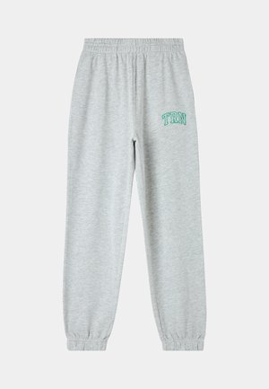 Pantaloni grigi in felpa con vita elastica, polsini alle caviglie e "TRN" ricamato in verde sulla coscia sinistra. Tessuto morbido.