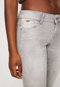 Grå denimjeans med en klassisk femficksdesign, subtila sömnadsdetaljer och en märkesetikett på midjan.