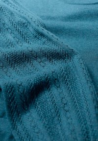 Mėlynosios žalios spalvos mezginys su tekstūriniu raštu ir atviromis siūlėmis, sukuriantis subtilų dizainą. Lygus paviršius, lengvas išvaizda.