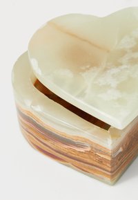 Scatola a forma di cuore con sfumature di marrone e crema a strati. Superficie liscia con un coperchio traslucido e variazioni di texture visibili.