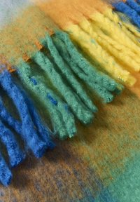 Uldblandet stof med livlige frynser i blå, grøn, gul og orange. Blød struktur med et gradientmønster.
