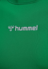 Grünes sportliches Shirt aus glattem Material, mit einem grauen "hummel"-Logo und einer Biene-Grafik auf der linken Seite.