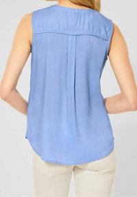 Ljusblå ärmlös blusa med ett plisserat ryggdesign, mjuk textur, rundad nederkant och subtila samlade halsdetaljer.