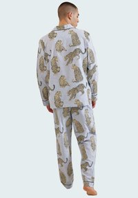 Conjunto de pijama de algodón en un color azul claro con un estampado de leopardo. Detallado con un cuello con muesca y ribetes en contraste en los puños.