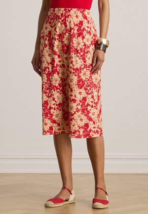 Mujer con falda midi floral en rojo y beige combinada con alpargatas rojas y pulseras doradas y de carey.