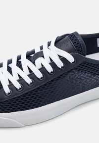 Námořnické síťové tenisky s bílými šňůrkami, s hladkým povrchem, kontrastními panely a kulatými očky na bílé gumové podrážce.