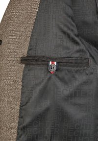 Bruine, gestructureerde stof aan de linkerzijde, gladde zwarte binnenkant met subtiele herhaalde merklogo's. Bevat een knop met rode, witte en blauwe accenten.