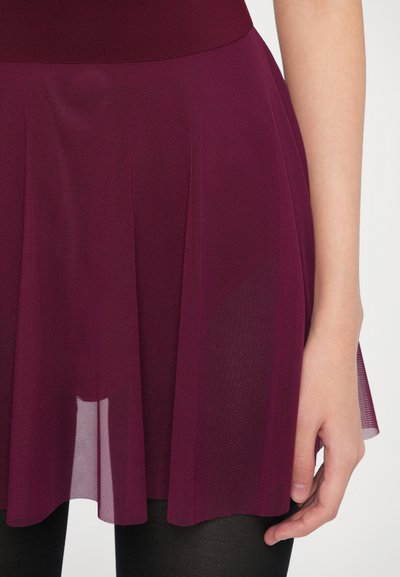 Φούστα μπορντό με αέρινο σχέδιο, κατασκευασμένη από ελαφρύ, διάφανο ύφασμα, με πιέτες στο τελείωμα. Συνδυασμένη με μαύρο καλσόν.