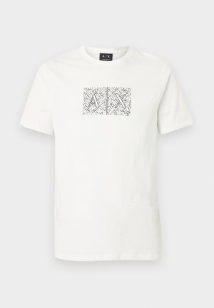 Weißes T-Shirt mit kurzen Ärmeln und Rundhalsausschnitt, mit einer schwarzen und weißen abstrakten Grafik, die überlappende "A"- und "X"-Buchstaben zeigt und mittig auf der Brust platziert ist.