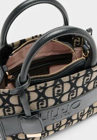 Schwarze Ledertasche aus bedrucktem Canvas mit doppelten Griffen, goldfarbenem Reißverschluss und mehreren Innenfächern; Markenlogo sichtbar.