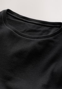 Black ribbed fabric t-shirt showcasing a round neckline and textured surface, with visible stitching details along the edges.