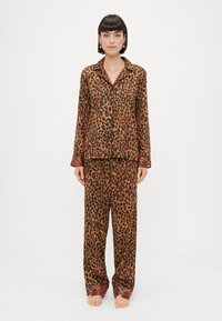 Pajama set z leopardjim vzorcem v rjavih odtenkih, ki vključuje srajco na gumbe z dolgimi rokavi in usklajenimi hlačami z okrašenimi manšetami.