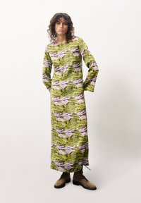 Langärmliges Kleid aus grünem Stoff mit einem Druck von Berglandschaften in rosa und lila Tönen, ergänzt durch ein knöchellanges Design und seitliche Schlitze.