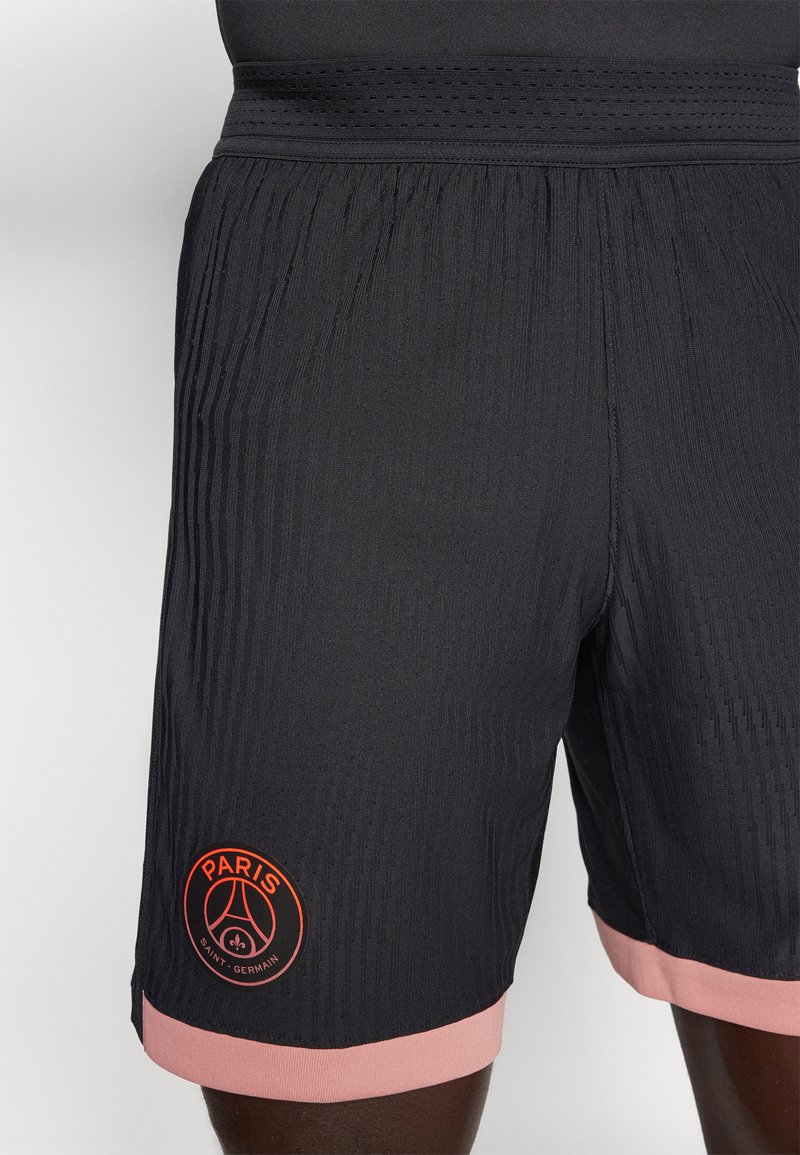 Schwarze Sportshorts mit geripptem Muster, ausgestattet mit einem rosa Saum und einem Logo mit "PARIS" und "SAINT-GERMAIN" in Orange.
