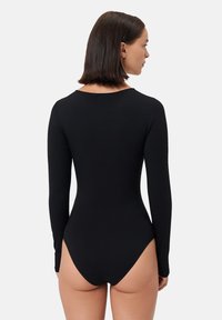 Černý dlouhý rukáv body z pružného materiálu; má nízký design zadní části a vysoký výřez na nohou. Hladká textura a přiléhavý střih.