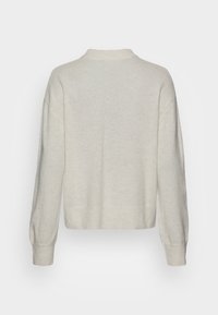 Pull tricoté couleur crème, avec un col montant, des manches longues, une coupe ample, et des poignets et un ourlet côtelés. Texture lisse.