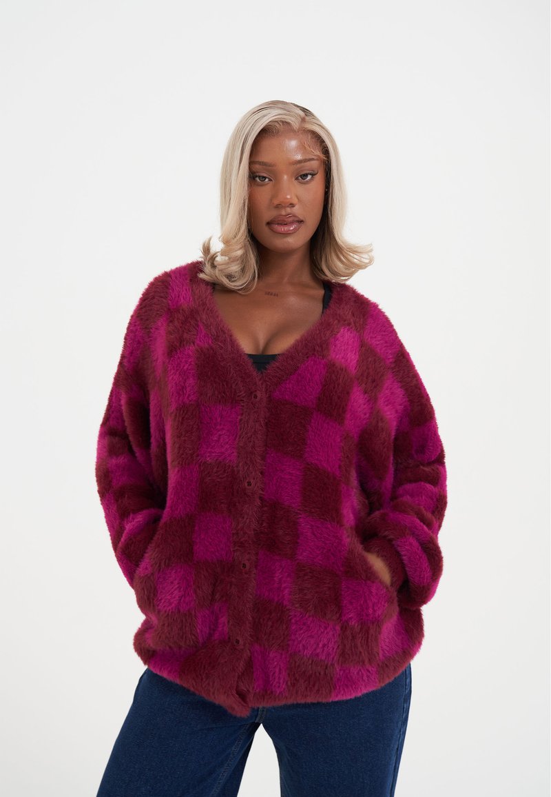 Měkký pletený svetr s knoflíky v kostkovaném vzoru magenta a bordó barvy, s výstřihem do V, zapínáním na knoflíky a dvěma bočními kapsami.