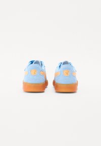 Blue suede sneakers with orange accents, featuring a textured sole, padded collar, and logo on the heel. Simplistic design, low-top style.