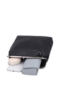 Monedero de cuero negro parcialmente abierto con smartphone, cartera gris claro y estuche beige para auriculares inalámbricos en su interior.