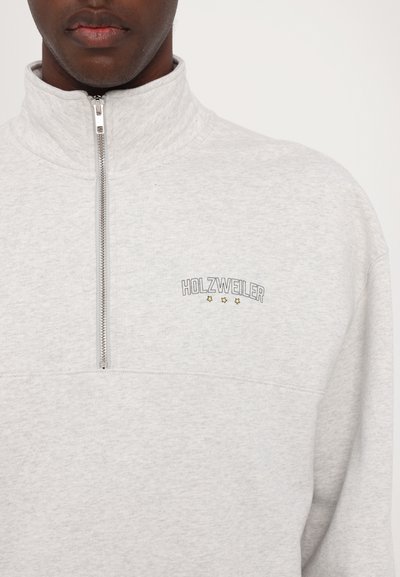 Svetlošedá mikina na zips s vysokým golierom, s vyšívaným logom "HOLZWEILER" a tromi hviezdami. Mäkkučká, textúrovaná látka.