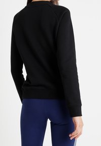 Svart sweatshirt med rund halsringning, raglanärmar och ribbade muddar. Mjuk tyg med slät textur, bakvy visad.