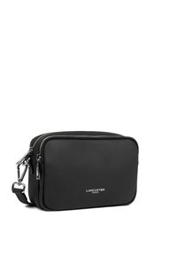 Borsa a tracolla sintetica nera con texture liscia, chiusura con zip, accessori in argento e logo "LANCASTER PARIS" in rilievo sul fronte.