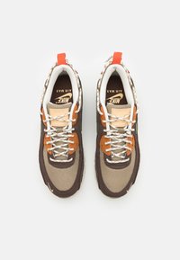 Nike Air Max Sneaker mit einer Mischung aus braunen, beige und orangefarbenen Materialien sowie Mesh- und Lederelementen. Mit beigen Schnürsenkeln und Logo.