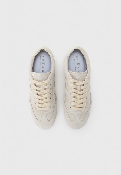 Ανοιχτό μπεζ σουέντ αθλητικά παπούτσια με κρεμ κορδόνια, στρογγυλεμένες μύτες και διακριτικές λεπτομέρειες ραφών. Λαστιχένιες σόλες και μαξιλαρωμένο εσωτερικό.