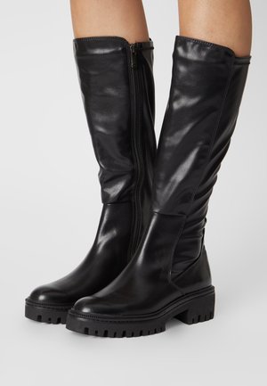 Black knee-high boots made of smooth leather, featuring a side zipper, chunky rubber sole, and gently slouched design.