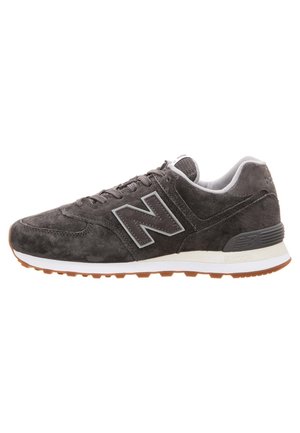 Mørkegrå ruskind New Balance sneaker med hvid mellemsål, gummi ydersål og fremtrædende "N" logo på siden.