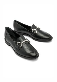 Czarne skórzane mokasyny o teksturowanym wykończeniu, z akcentem z srebrnego metalu i zaokrąglonym noskiem. Niskie, wygodne obcasy.