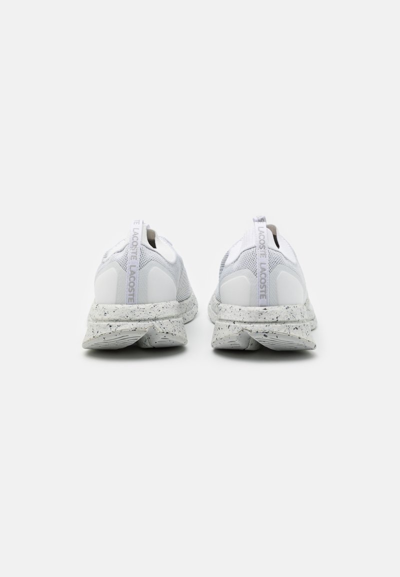 Baskets blanches avec une tige en maille et une semelle en caoutchouc. Présente une semelle intermédiaire teintée et un logo "LACOSTE" sur l'étiquette au talon. Forme arrondie.