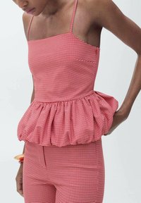 Red and white gingham peplum top with spaghetti straps, featuring a gathered waistline and smooth, fitted bodice.