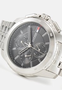 Montre chronographe en acier inoxydable avec un cadran texturé noir, des accents argentés, trois sous-cadrans et un bracelet en maillons métalliques.